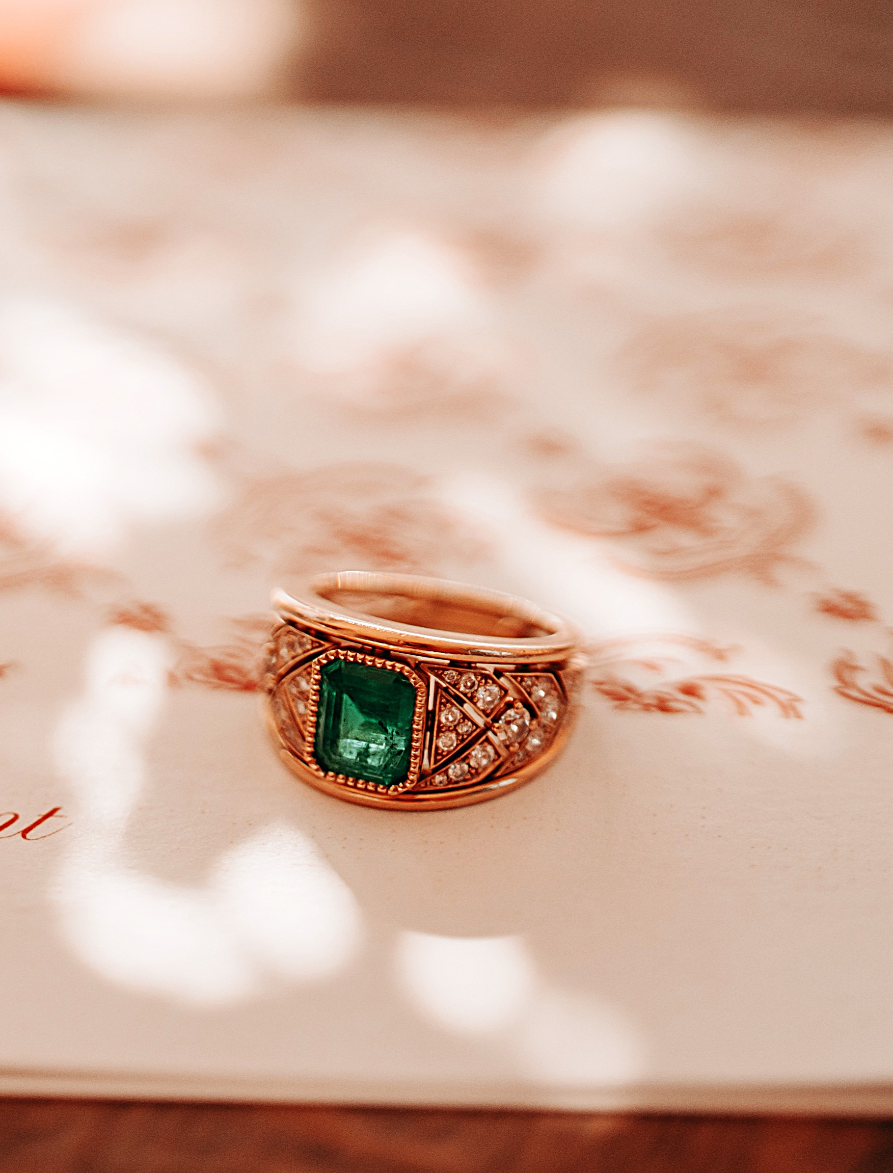 L'image représente un bijou, c'est une bague ruban en or jaune sertie d'une magnifique émeraude et de diamants